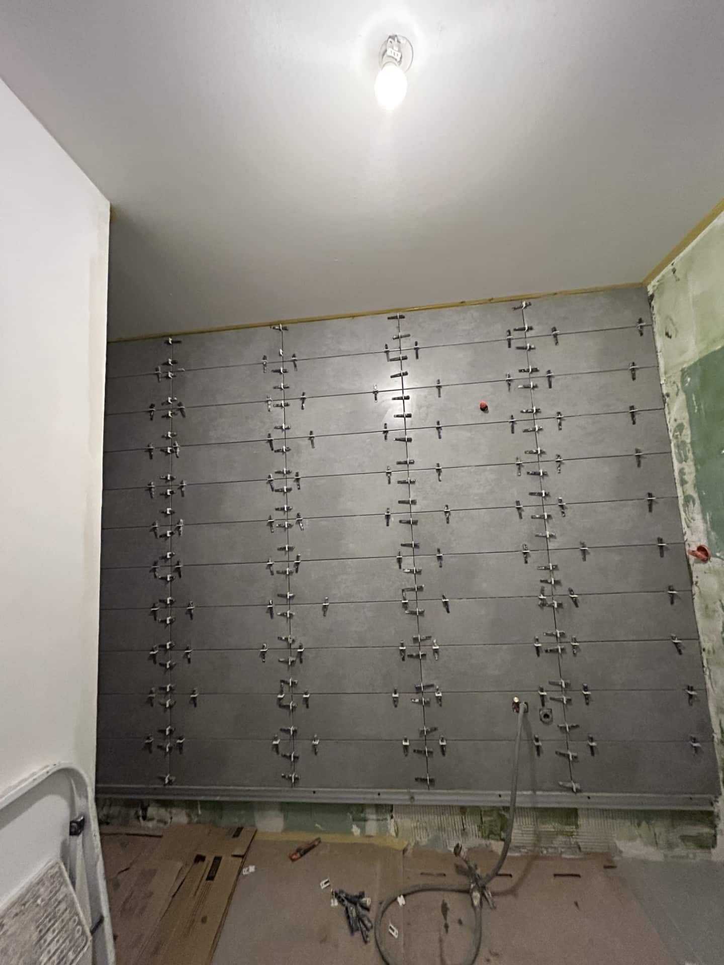 Pose de carrelage gris avec système de nivellement.