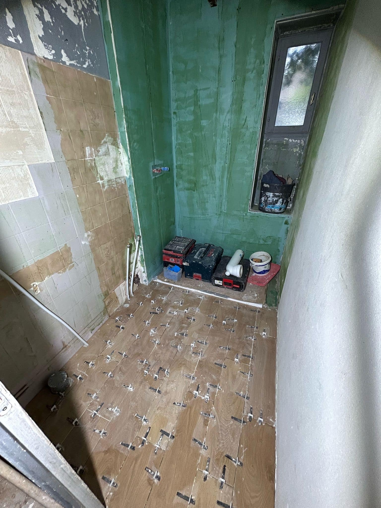 Rénovation de salle de bain : pose de carrelage imitation bois avec croisillons et murs étanches.