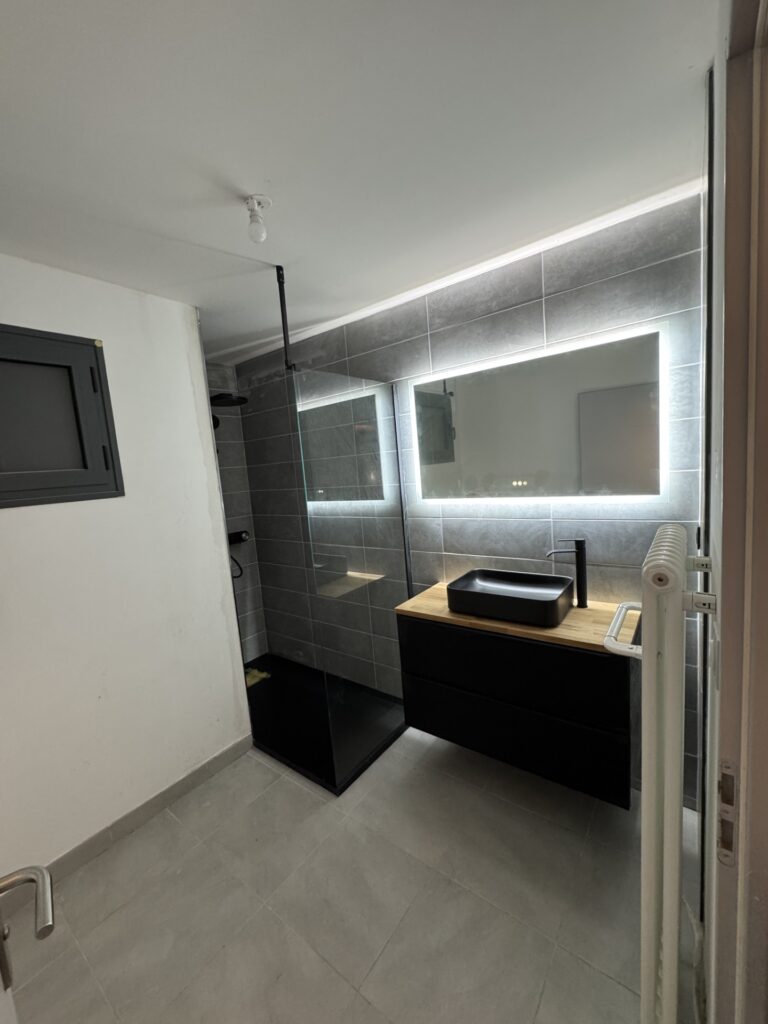 Salle de Bain Moderne : Douche Italienne et Meuble Vasque Noire Salle de bain moderne : douche vitrée, vasque noire sur meuble bois et miroir LED rétroéclairé.